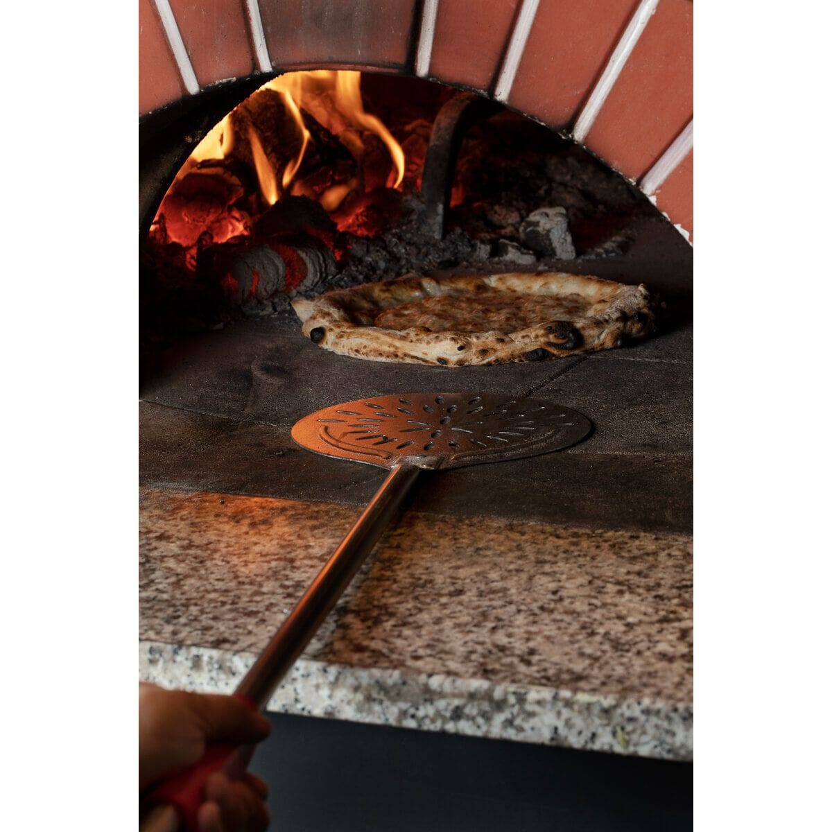 Cerutti pizza turner being used inside a pizza oven