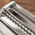 Close-up of a pasta maker with metal rollers on a wooden surface