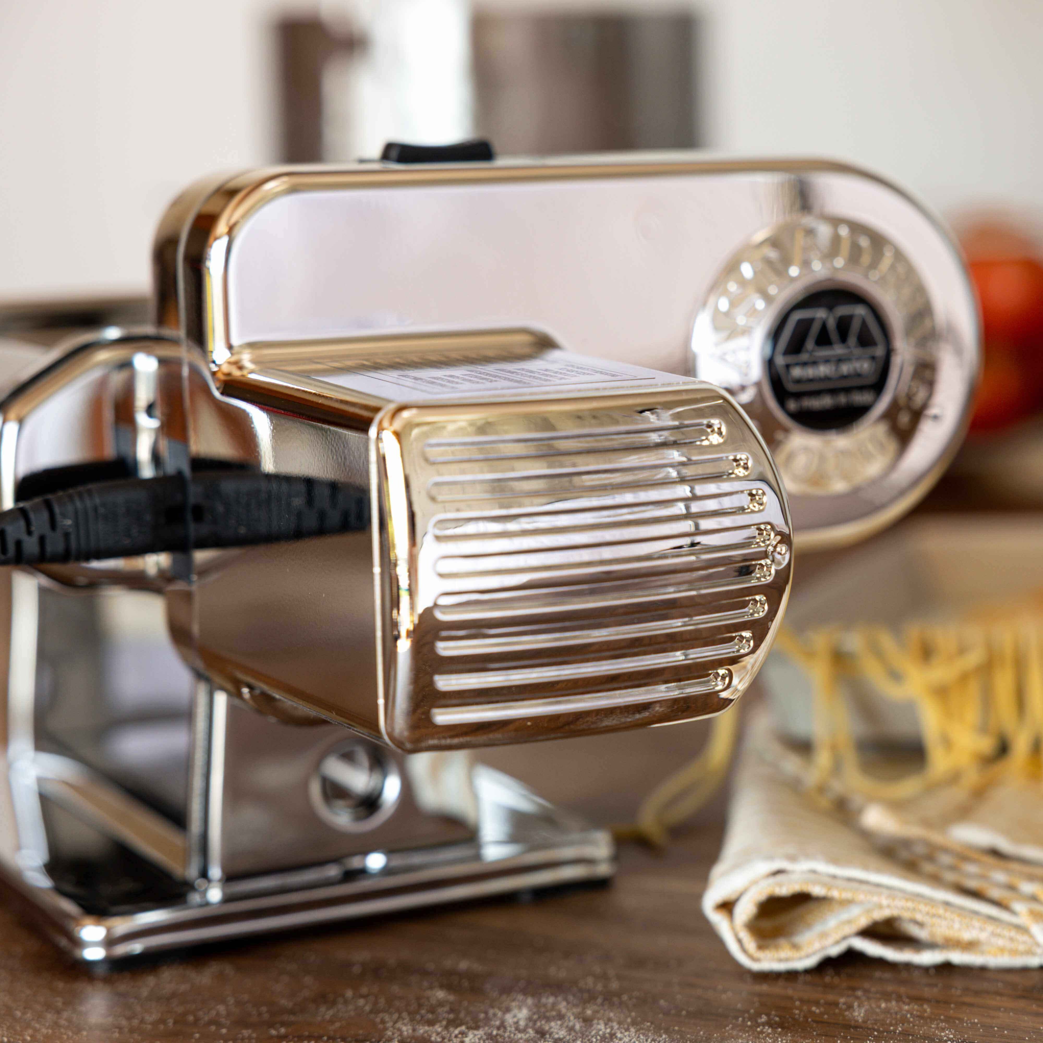 Pasta maker with fresh pasta on a kitchen counter
