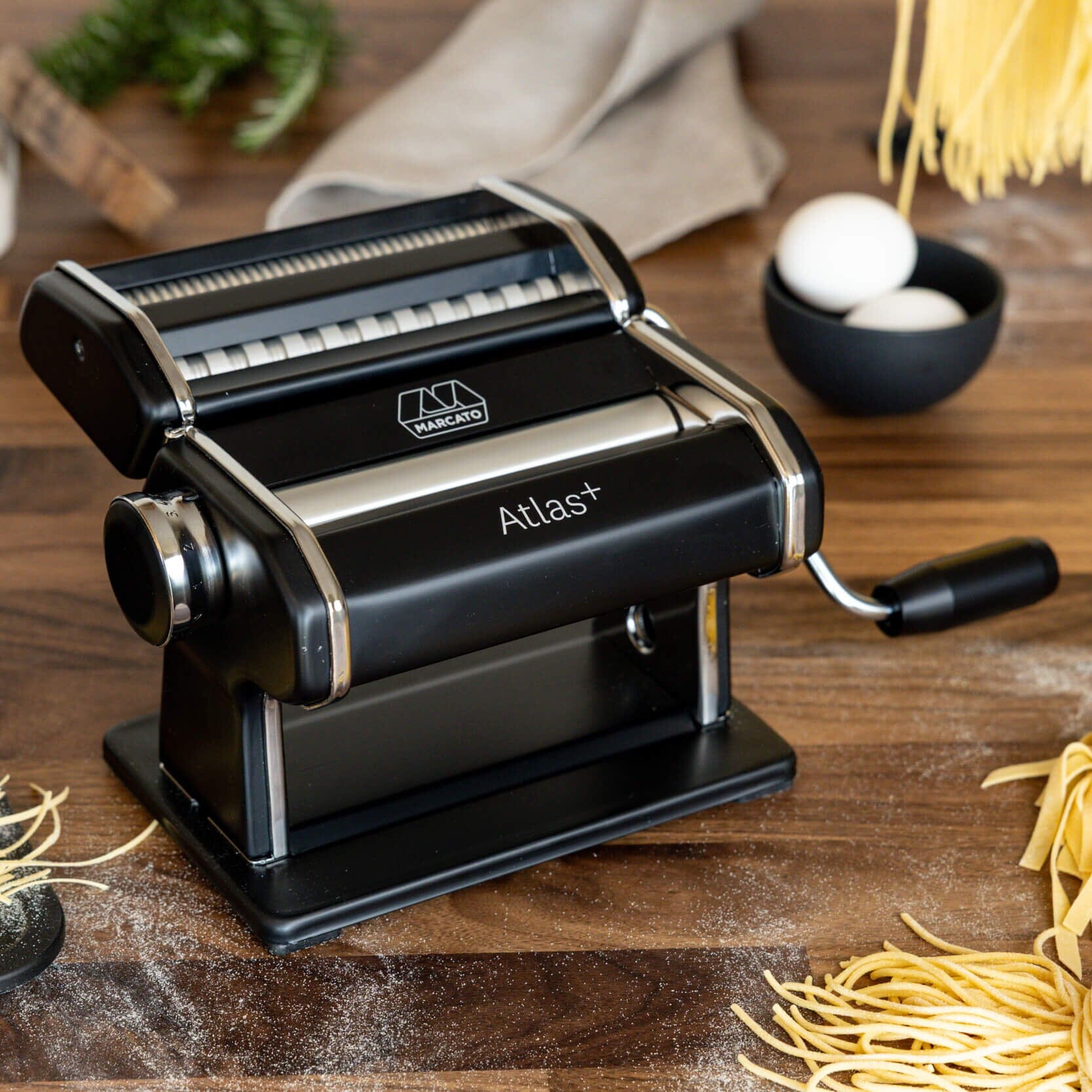 Pasta maker with fresh pasta on a wooden surface
