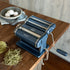 Pasta maker on a wooden table with fresh pasta strands