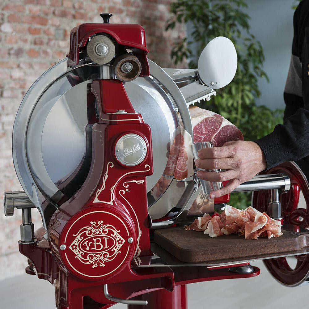 Red Berkel Volano B114 flywheel slicer being used with Berkel ham tongs cutting meat
