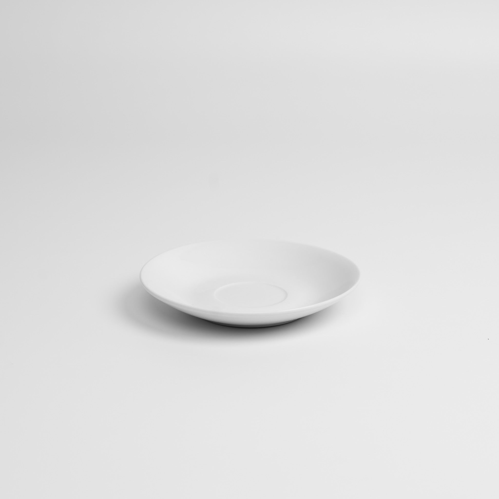 White porcelain saucer on a light gray background