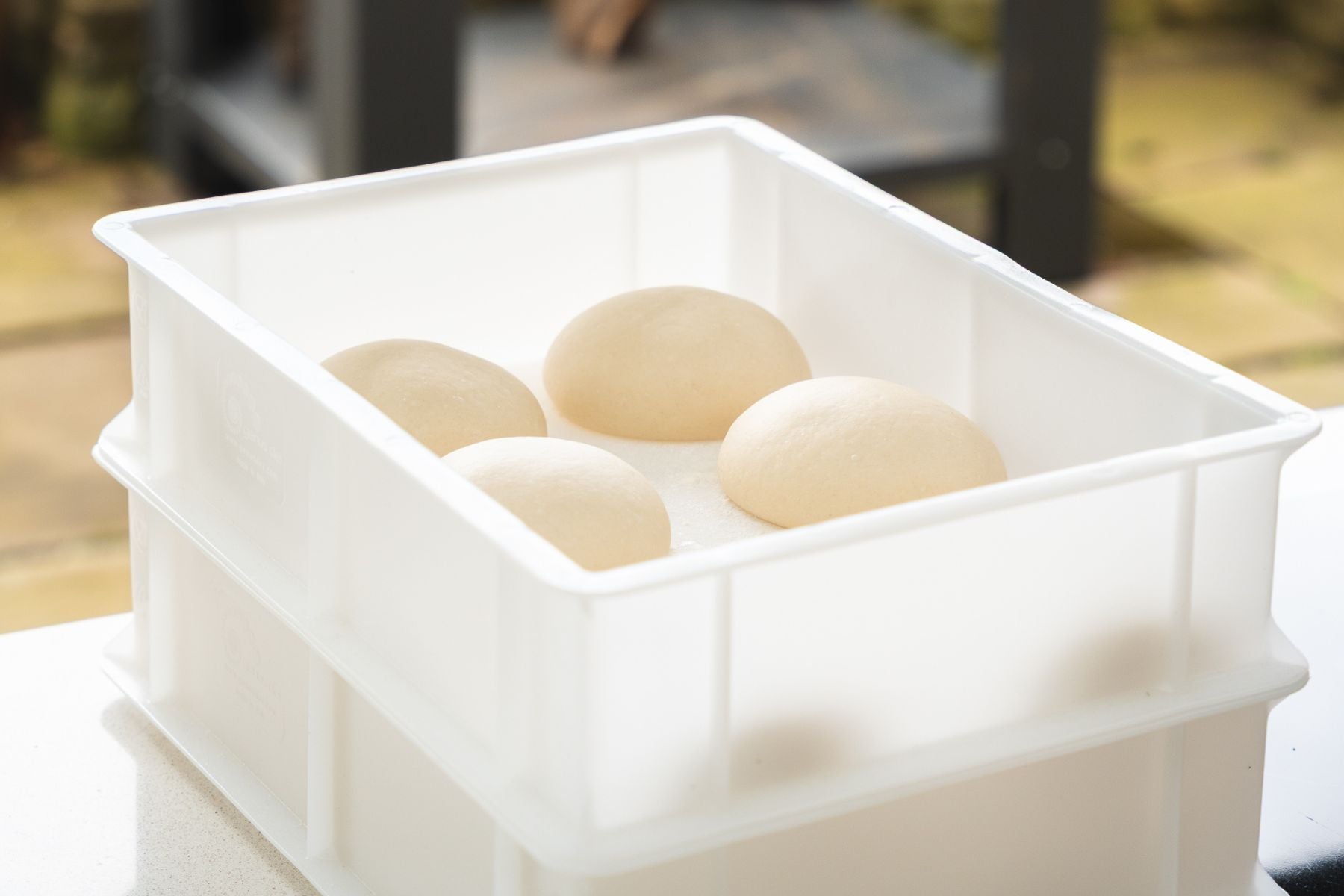 Pizza dough in white dough proofing boxes.