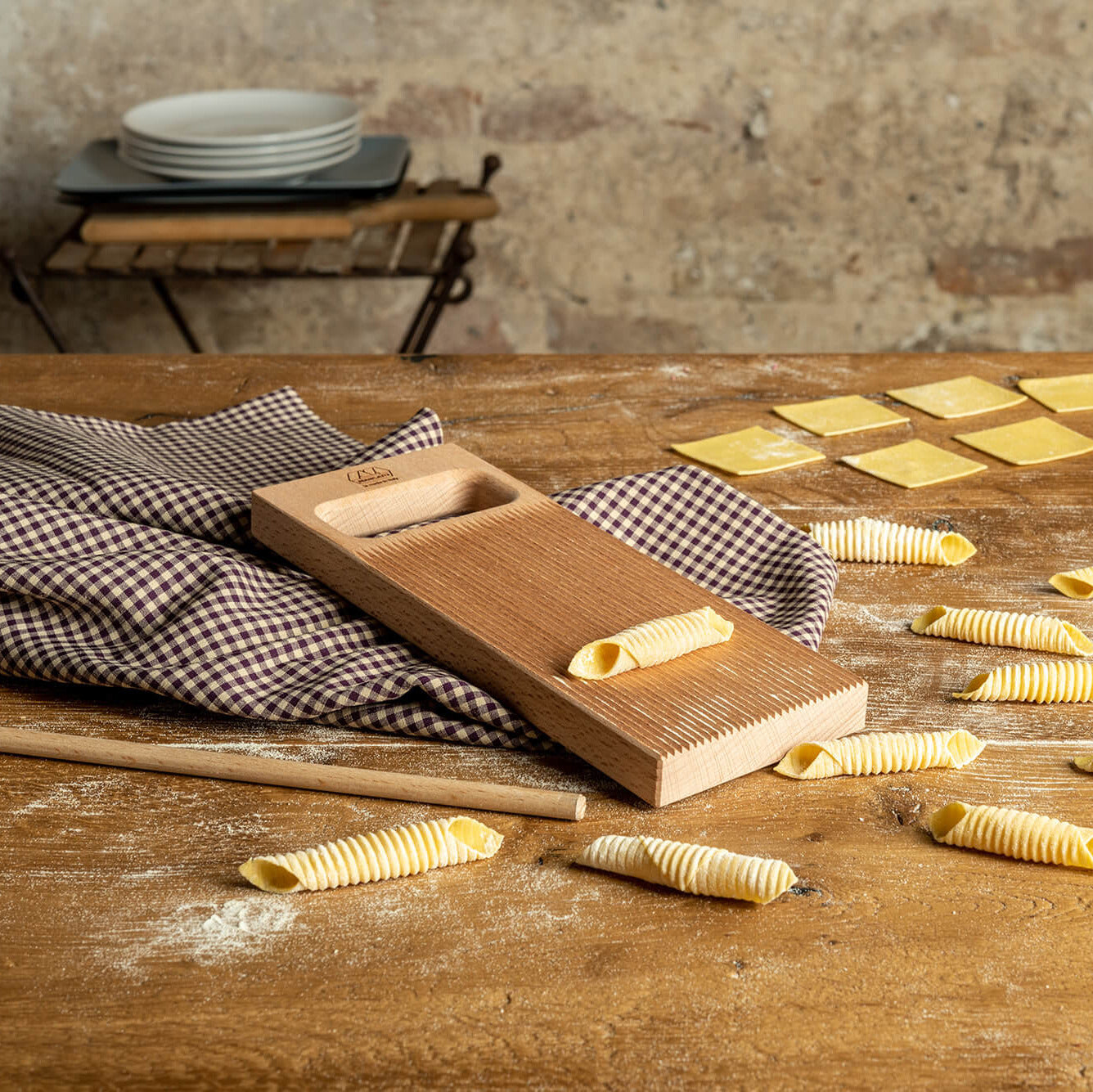 Marcato Rigagnocchi gnocchi and garganelli paddle with rolling pin next to handmade garganelli on a wooden bench