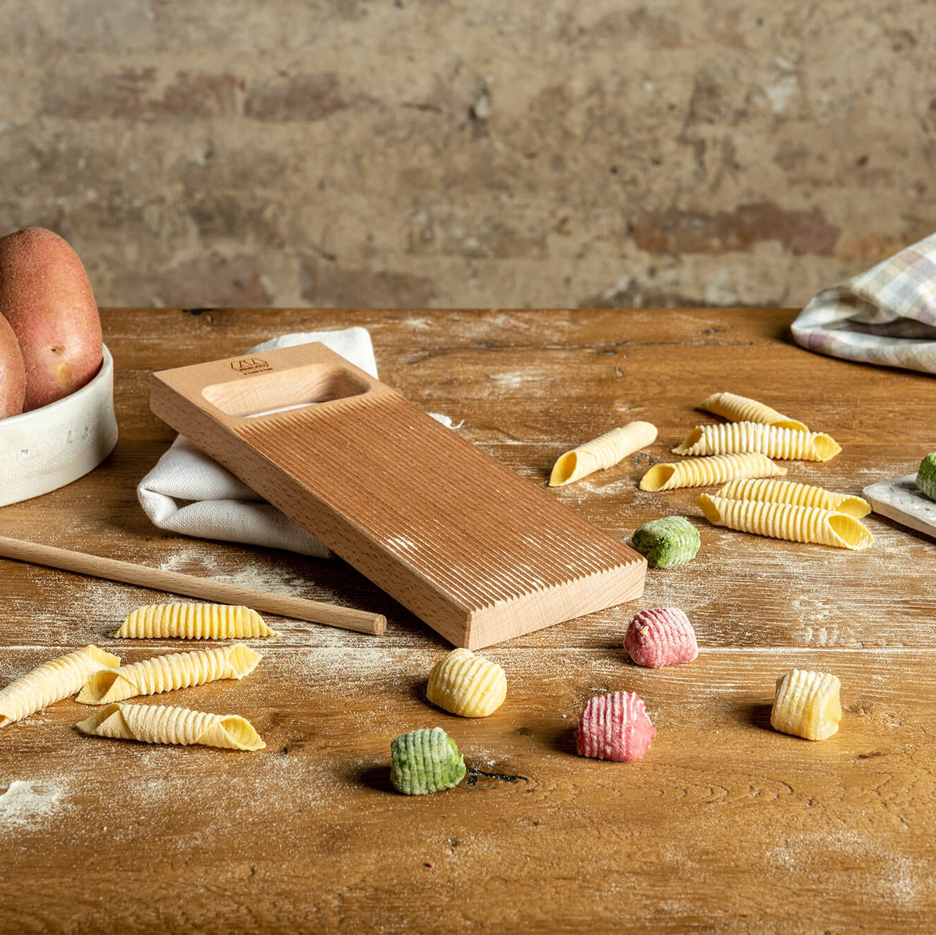 Marcato Rigagnocchi gnocchi and garganelli paddle with rolling pin next to handmade gnocchi on a wooden bench