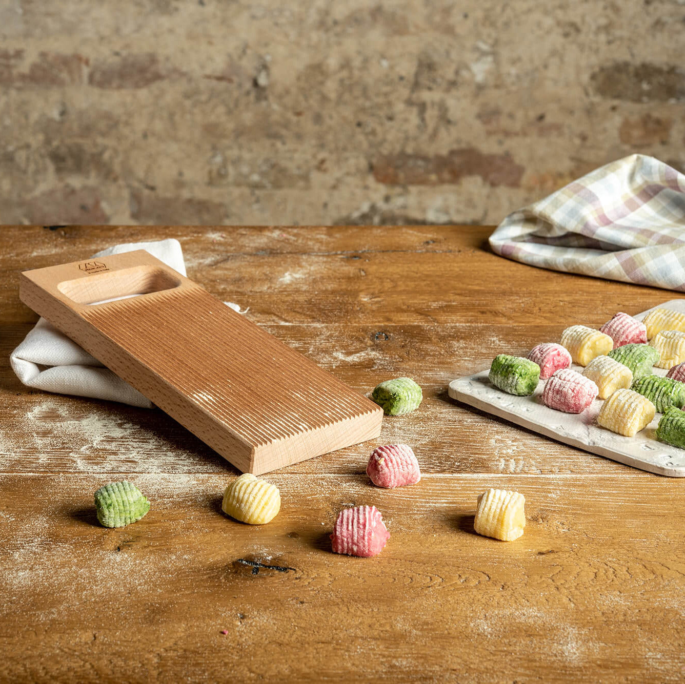 Marcato Rigagnocchi gnocchi and garganelli paddle with rolling pin next to handmade gnocchi on a wooden bench