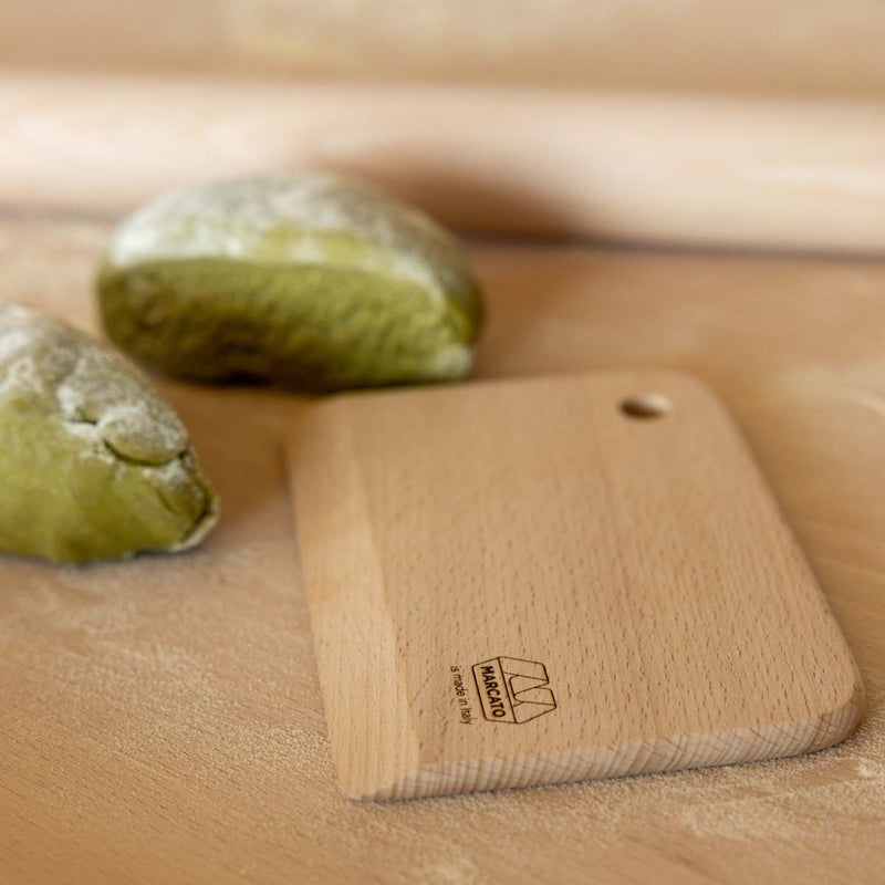 Wooden dough scraper with Marcato logo on a wooden bench