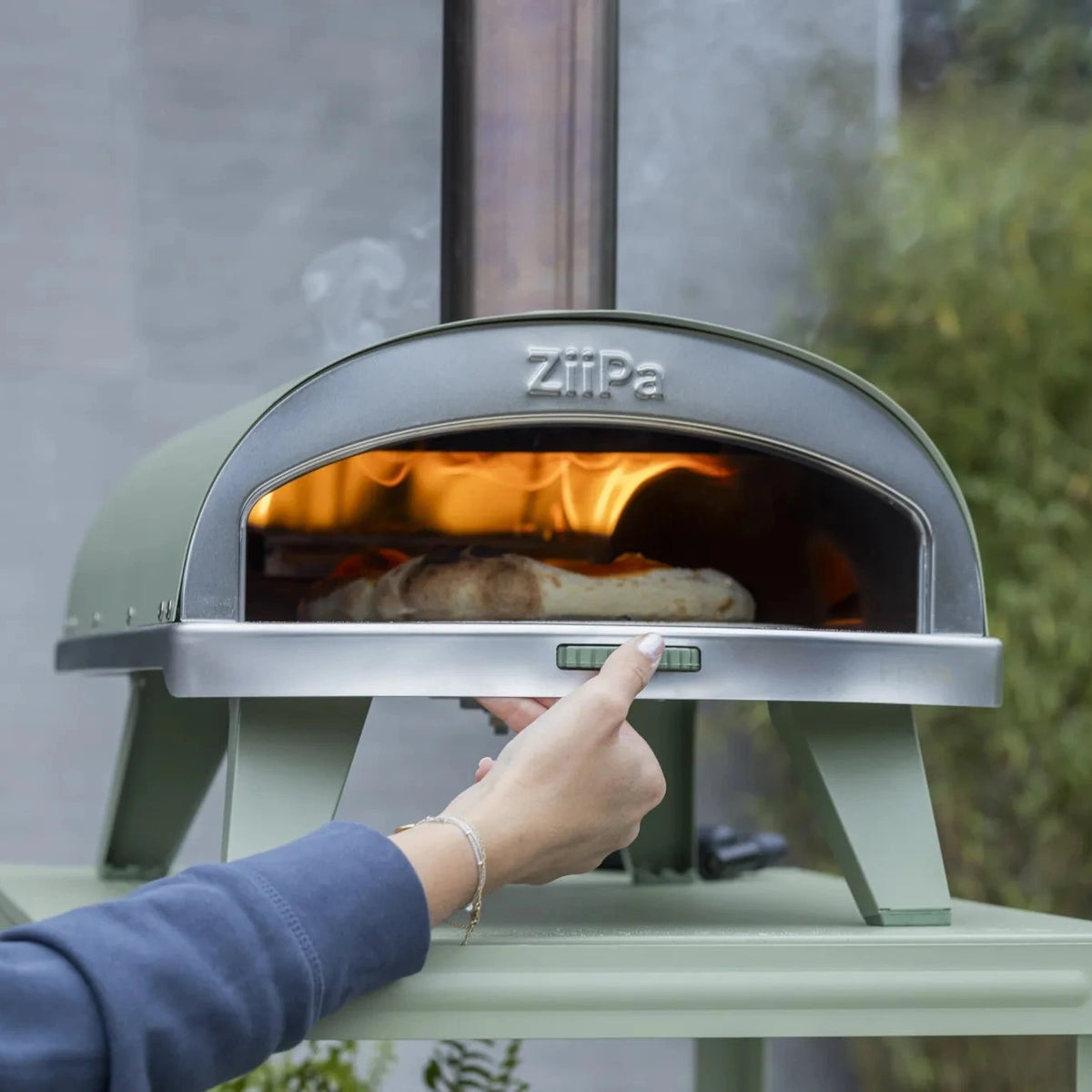 ZiiPa Piana wood-fired pizza oven in Eucalyptus outdoors in a garden setting
