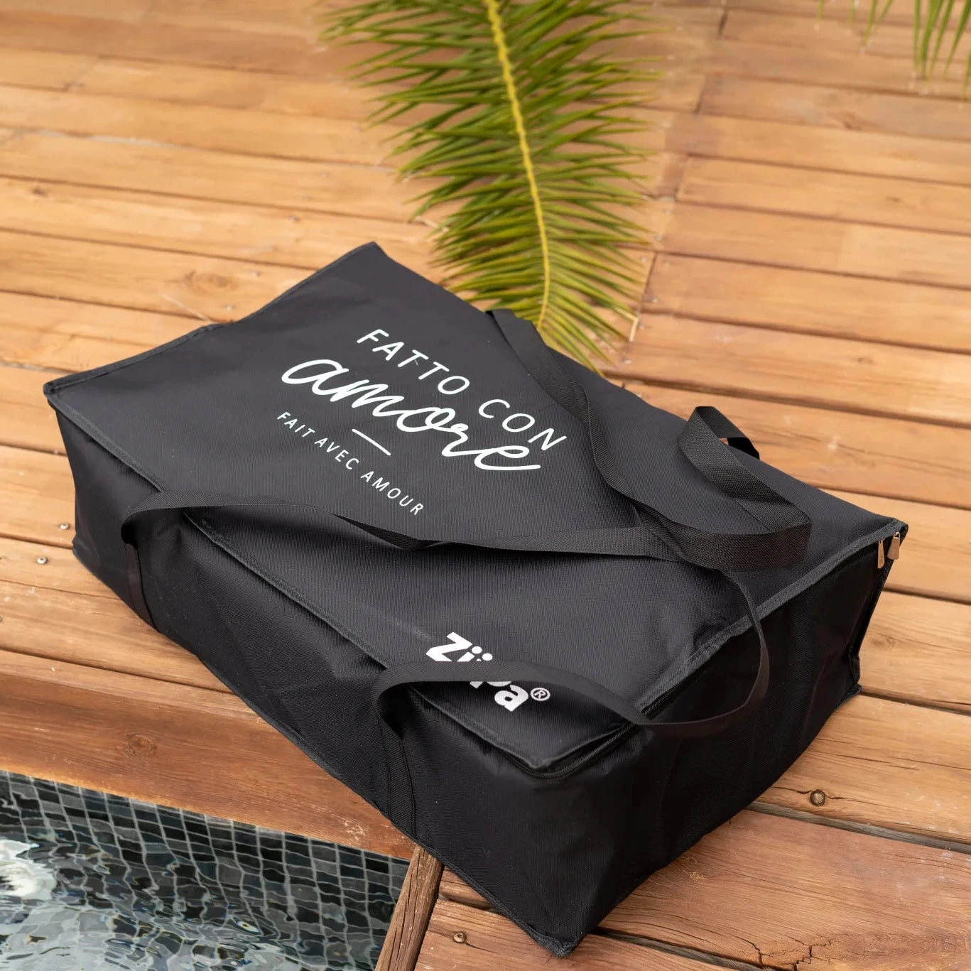 Front view of a Fontana travel bag for ZiiPa Piana Pizza Oven in Charcoal on wooden decking next to a pool