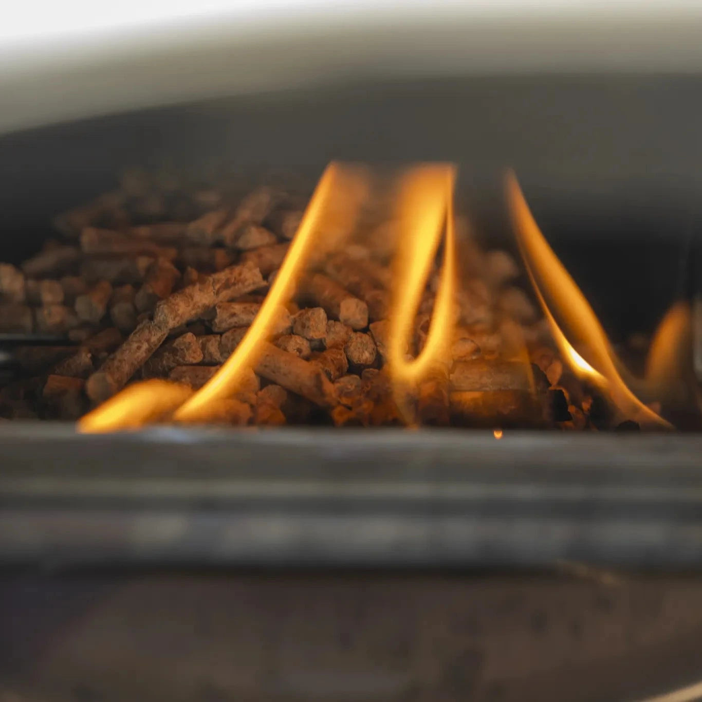 Wood pellets being ignited in a Piana pizza oven with flames