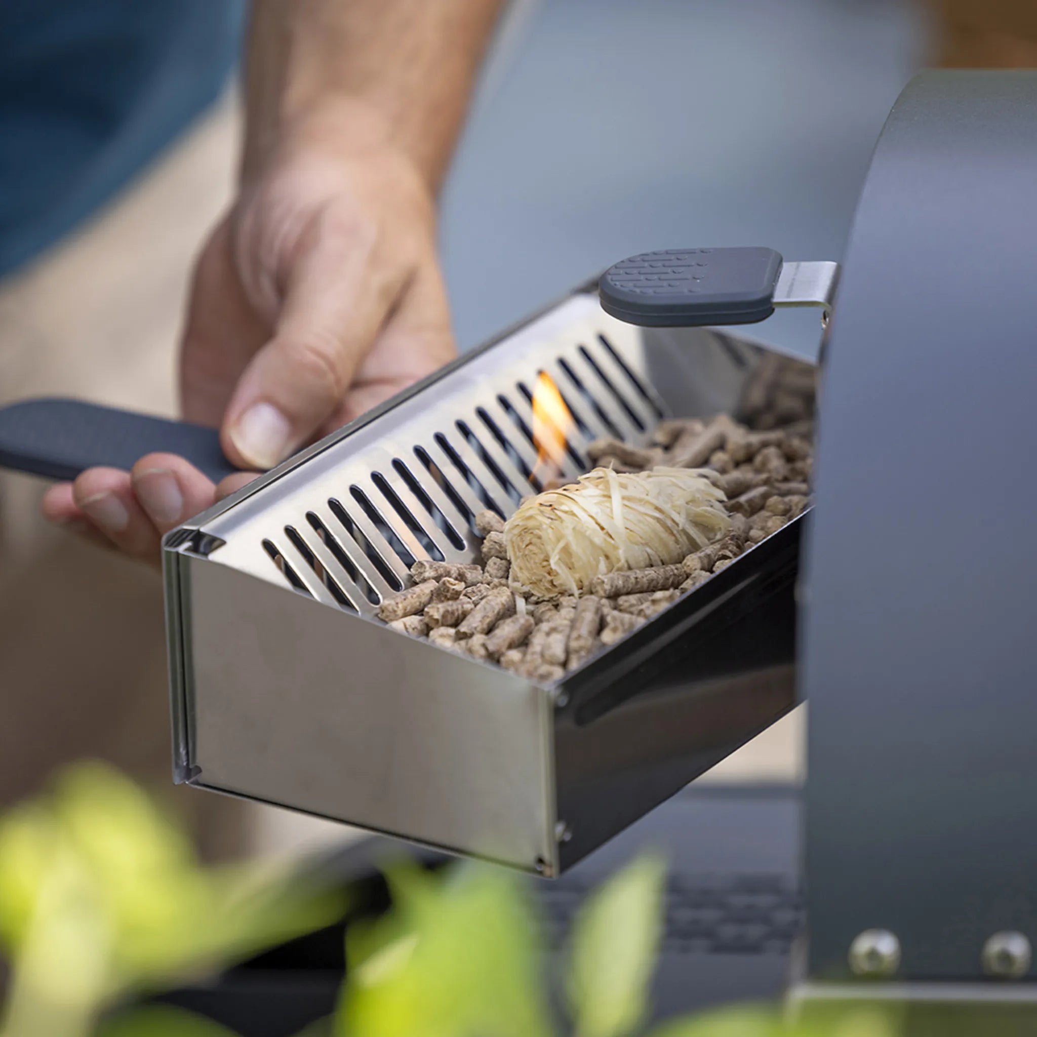 Person starting a fire with ZiiPa beech wood pellets and a fire starter in the fuel drawer for the Piana pizza oven