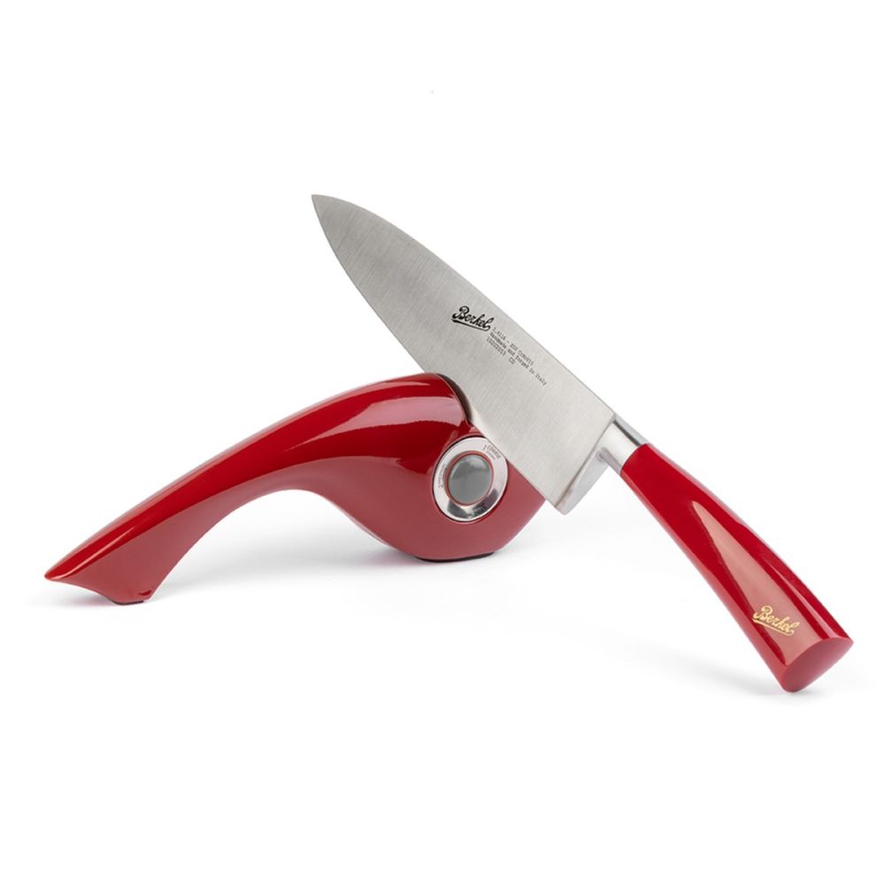 Berkel Manual Knife Sharpener being used with a red Elegance chef's knife on a white background