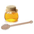 Jar of honey with a wooden dipper on a white background