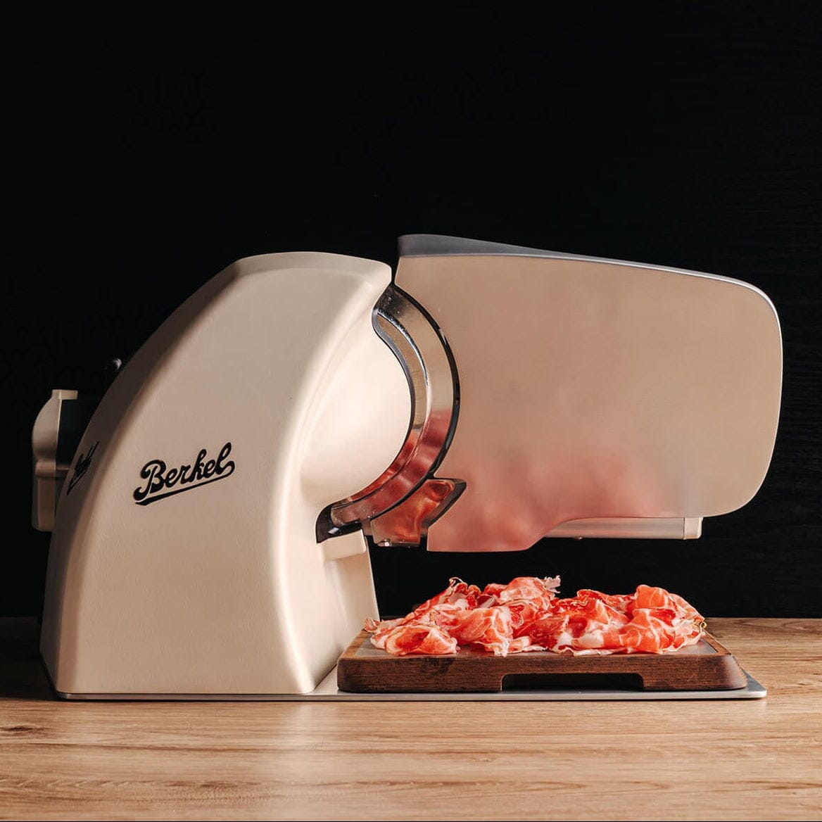 Cream Berkel Home Line Plus 200 Food Slicer with the Home Line Plus cutting board with cut prosciutto placed on top.
