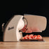 Cream Berkel Home Line Plus 200 Food Slicer with the Home Line Plus cutting board with cut prosciutto placed on top.